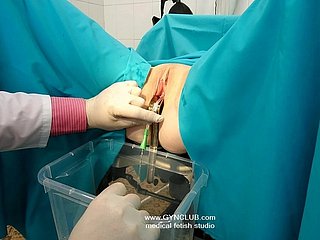 В клинической обстановке гинекологического кабинета профессиональные границы размываются, поскольку осмотр врача становится все более интимным. Спецификатор из нержавеющей стали широко раздвигает нежную кожу под резким флуоресцентным светом, обнажая блестящие розовые складки, уже реагирующие на прикосновение. То, что начинается как обычная пальпация, трансформируется, когда пальцы в перчатках проникают глубже, чем необходимо, обнаруживая чувствительные места, от которых у пациентки сжимаются пальцы ног. Стремя дребезжат, когда прикосновение врача становится целенаправленным и дразнящим, умело стимулируя, сохраняя при этом видимость медицинского авторитета. Когда пациентка выгибает спину и стонет от неожиданного удовольствия, профессиональный фасад рушится, обнажая необузданное желание под белым халатом.
